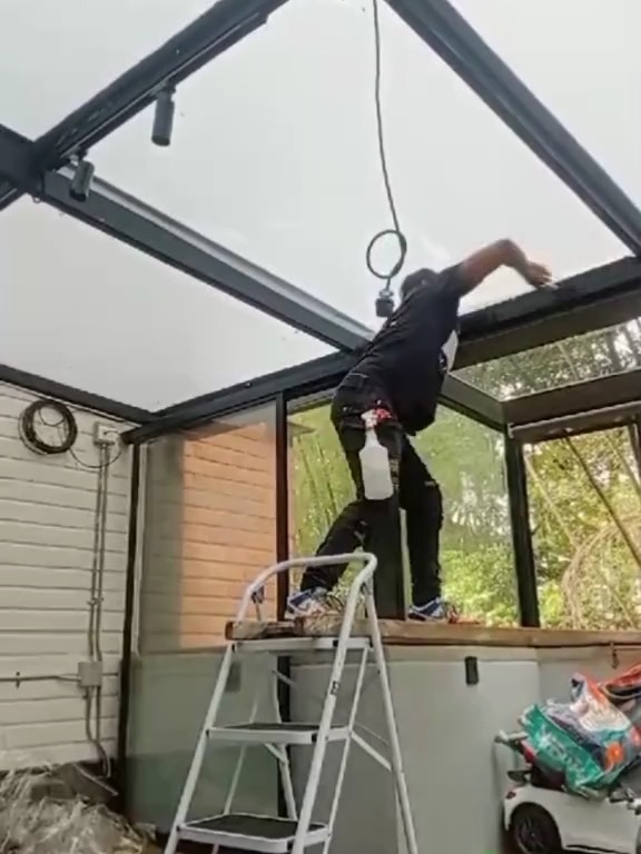 Técnico instalando película en un techo de vidrio