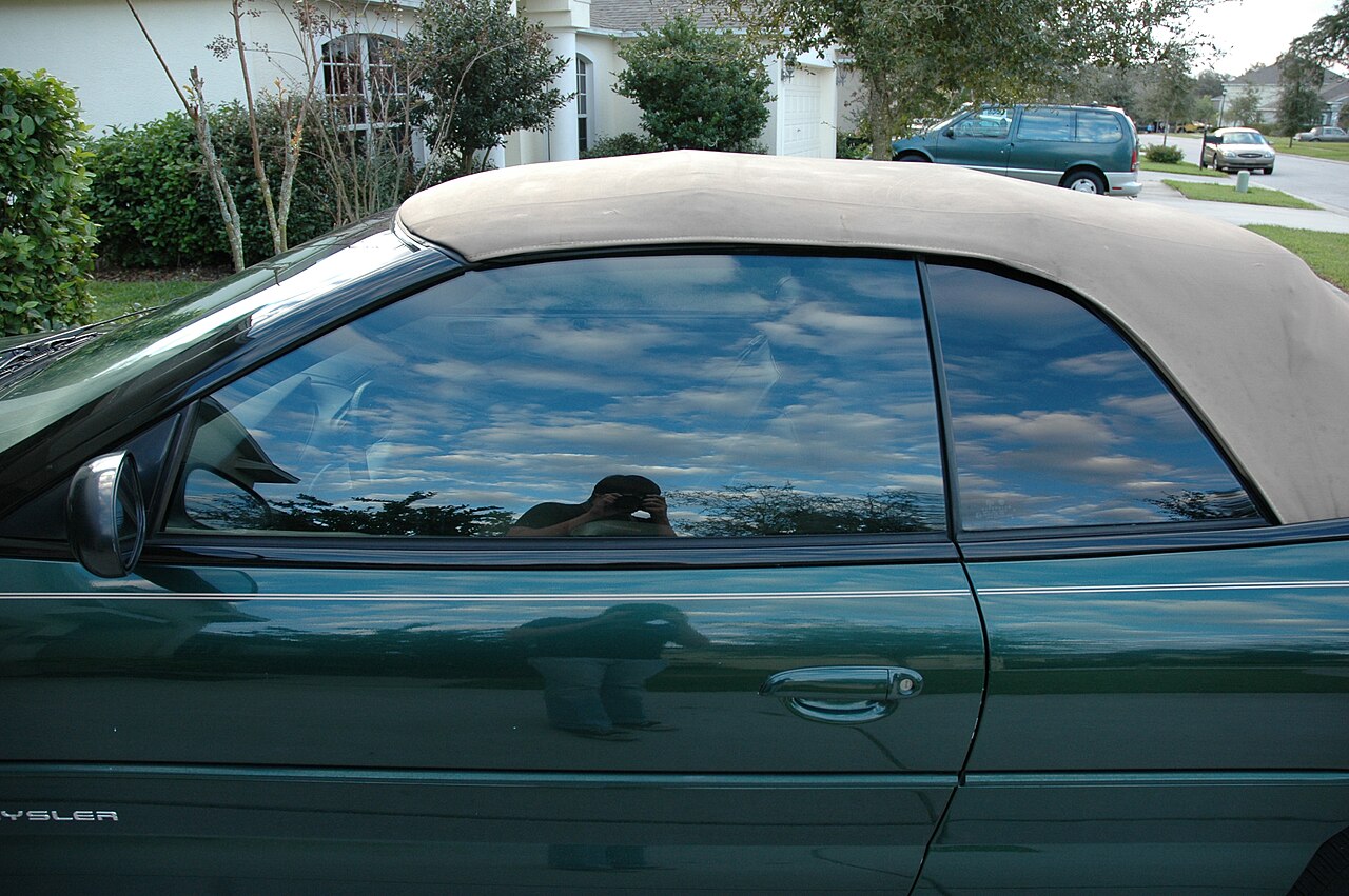 Ventana lateral de un carro con polarizado reflejando el cielo